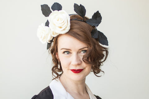 Miss Poppins wearing a paper flower crown with black crepe paper leaves and a large white crepe paper rose