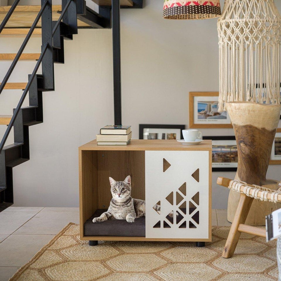 A small cat is sitting in her cat house.