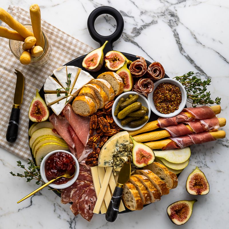 Round black serving board with cheese and charcuterie