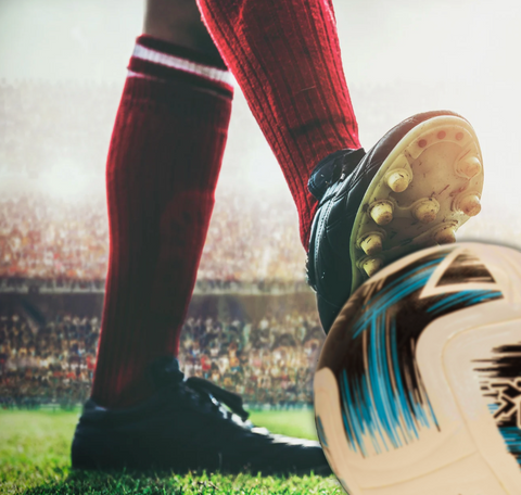Image of a footballers feet, wearing shin pads under his socks, one standing, the other on a football,