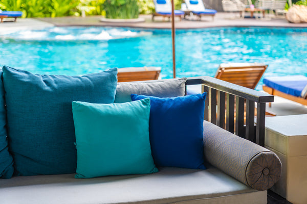 ourdoor cushions on garden furniture by a pool. 