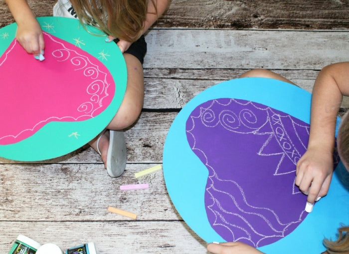 Two children creating a DIY chalkboard with pink and purple paints. 