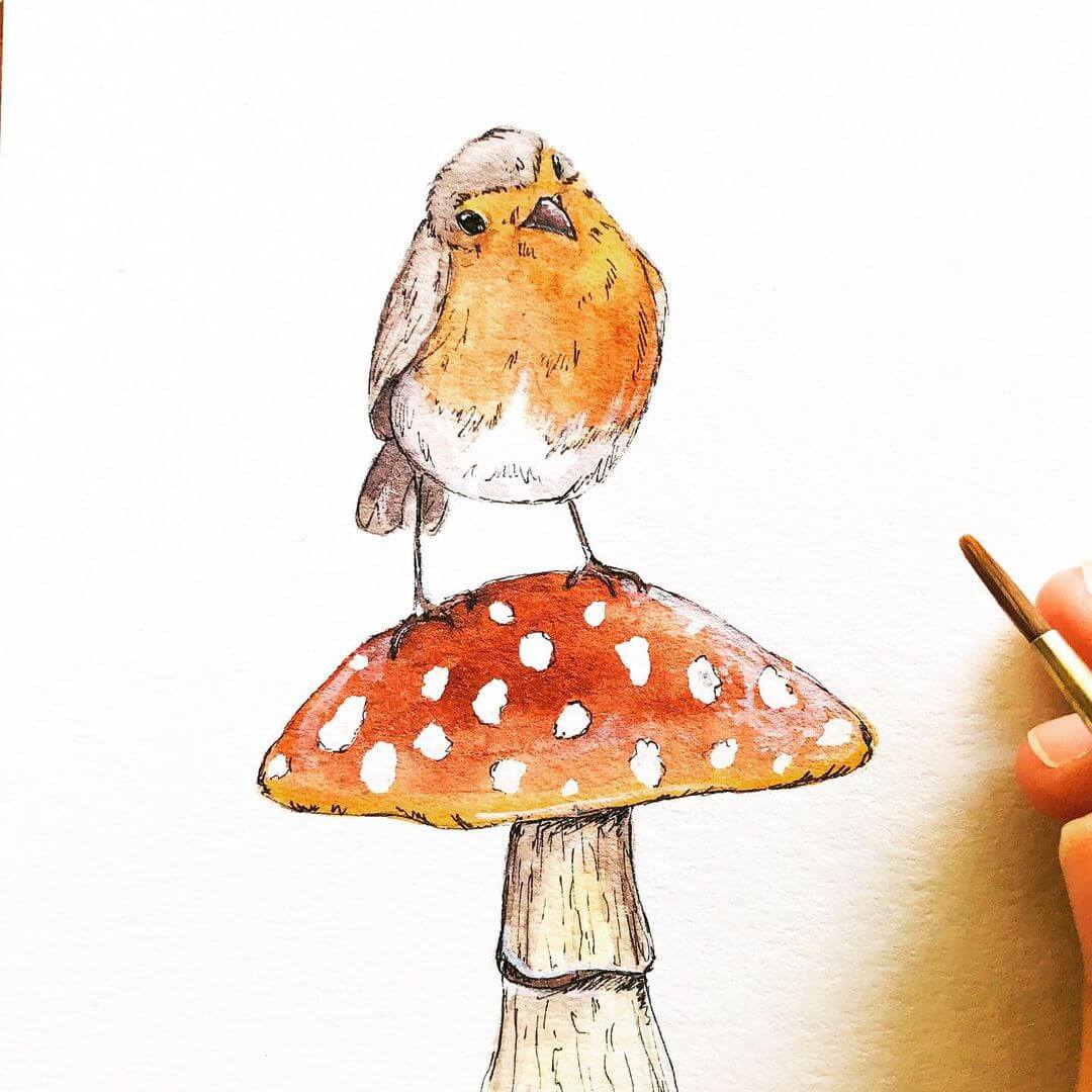 Bird standing on a toad stool drawn in watercolour with a brush next to it.