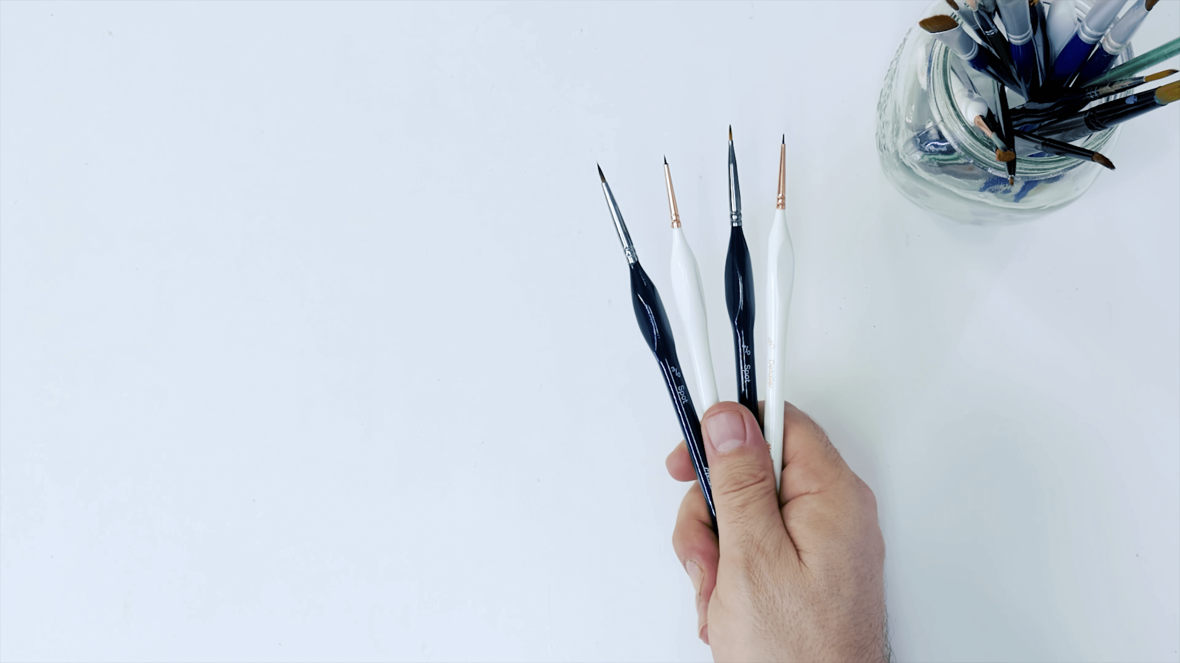 Four different sized detailer brushes being held in hand.