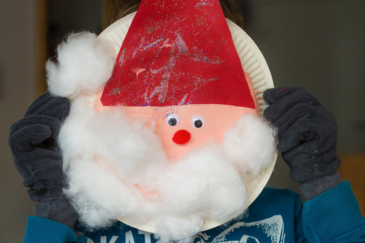 Hand holding a paper plate to look like Santa Claus.