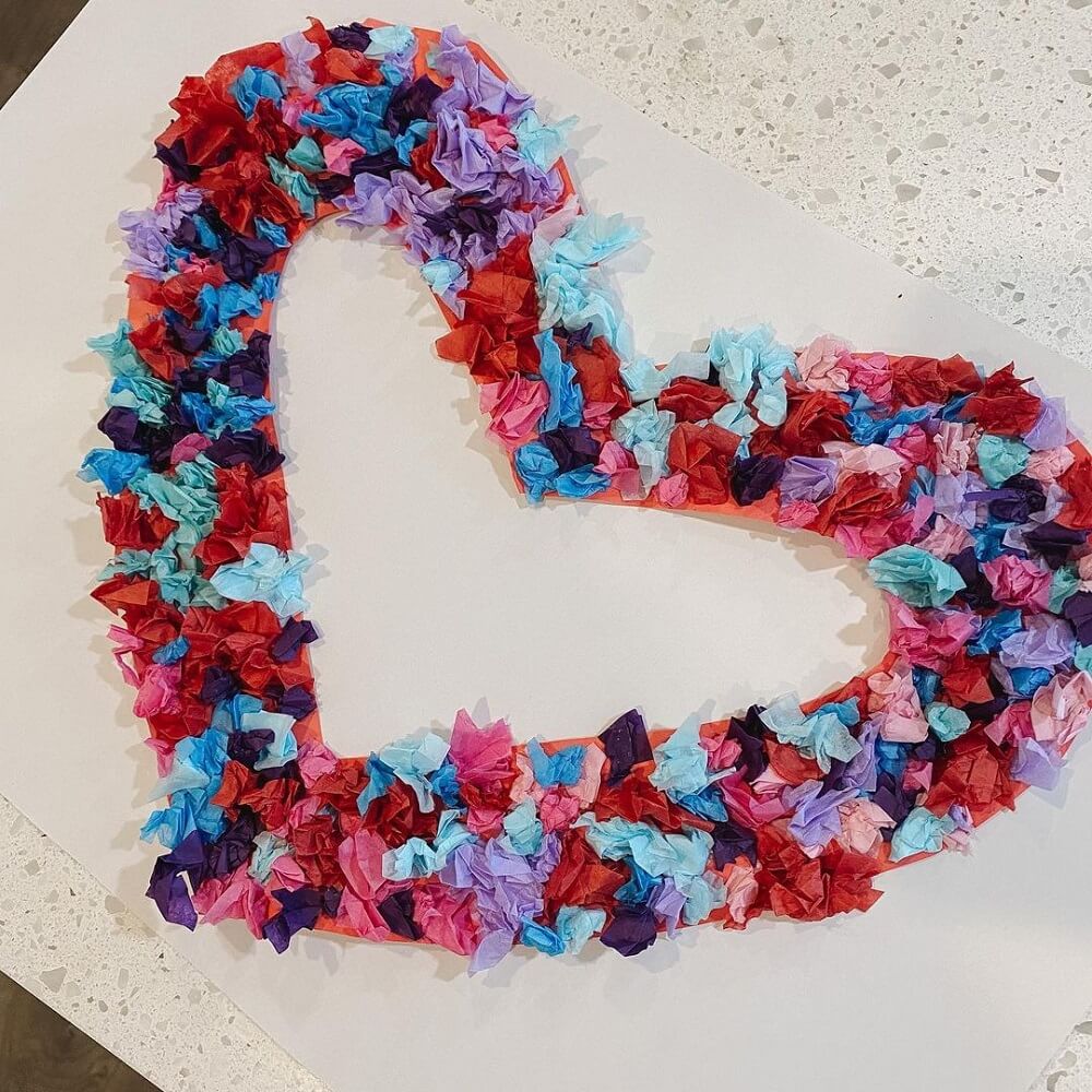 A paper love heart with colourful tissue paper scrunched on top to decorate.