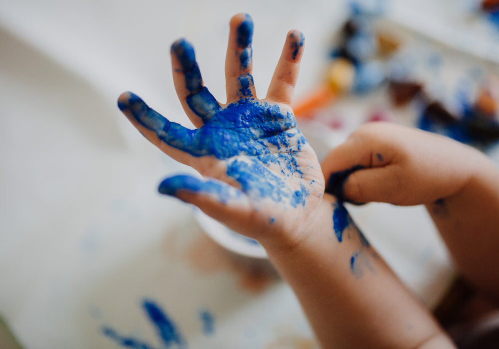 A child's hand painted blue for a handprint activity.