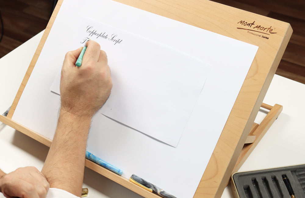 Hand writing with calligraphy pen on a wooden table top easel.