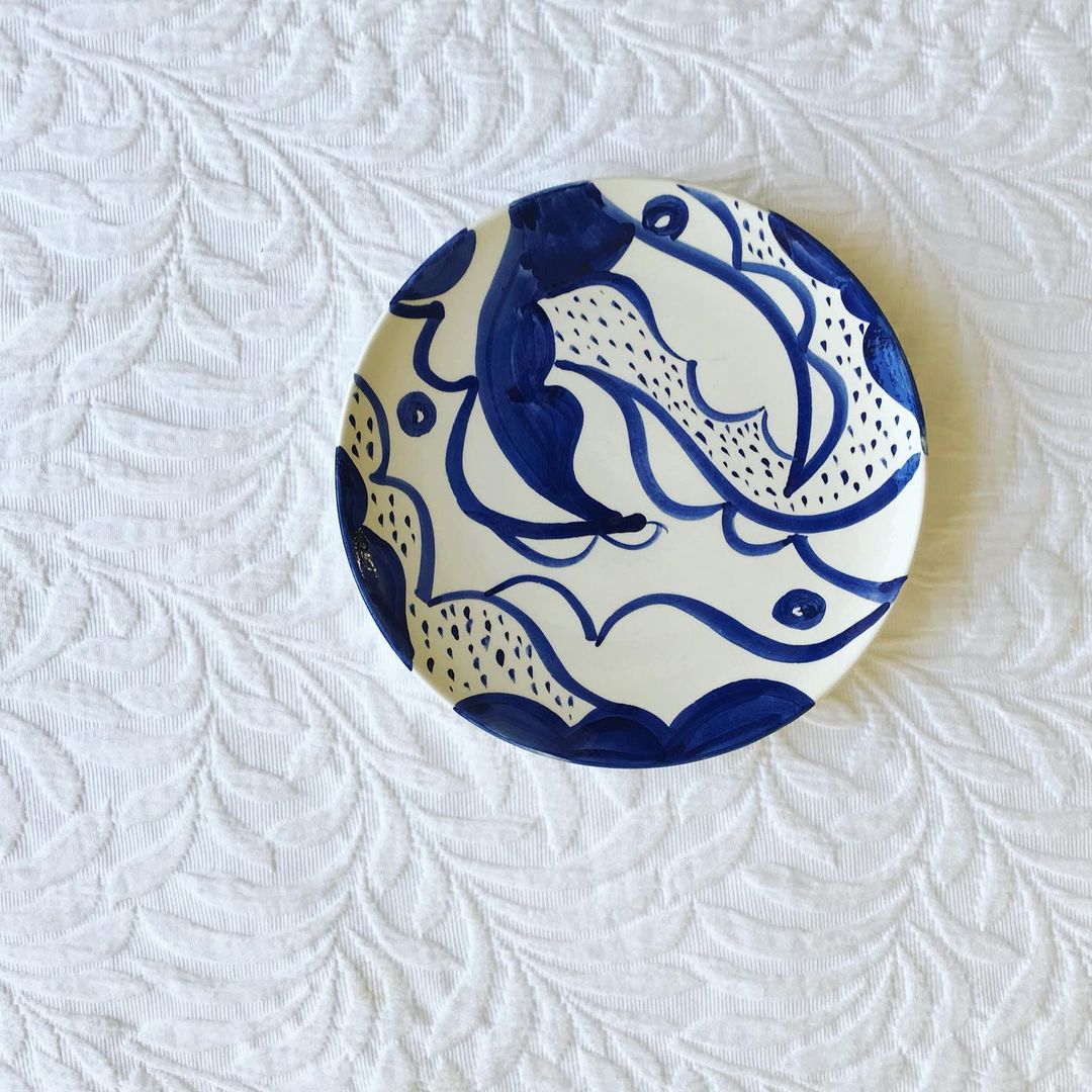 A white bowl hand painted with Mediterranean style pattern using dark blue ceramic paint.