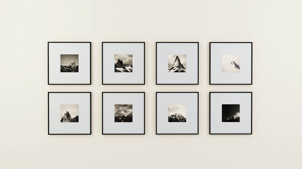 Gallery wall of black and white monochrome mountains framed on a white wall in black frames.