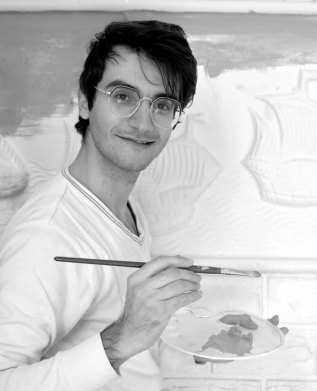 Grey scale photograph of artist Ahmad Akrum holding a paint brush and wooden palette.