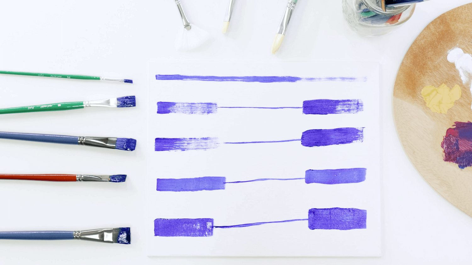 Blue paint lines of various flat oil paint brushes with the brush next to each paint stroke.