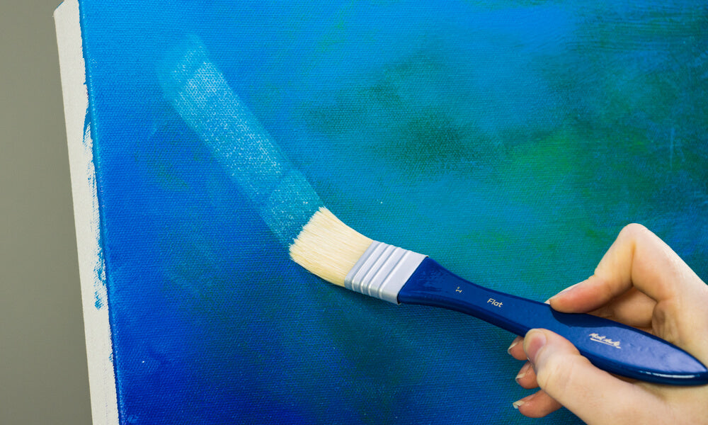 A brush brushing the blue canvas with an adhesive.