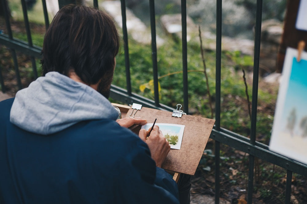 Woman painting watercolours in a green park.