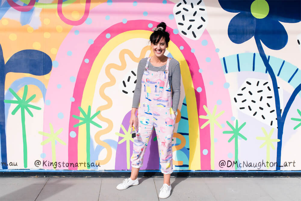 Deb McNaughton next to a window mural at Shirley Burke theatre Melbourne.