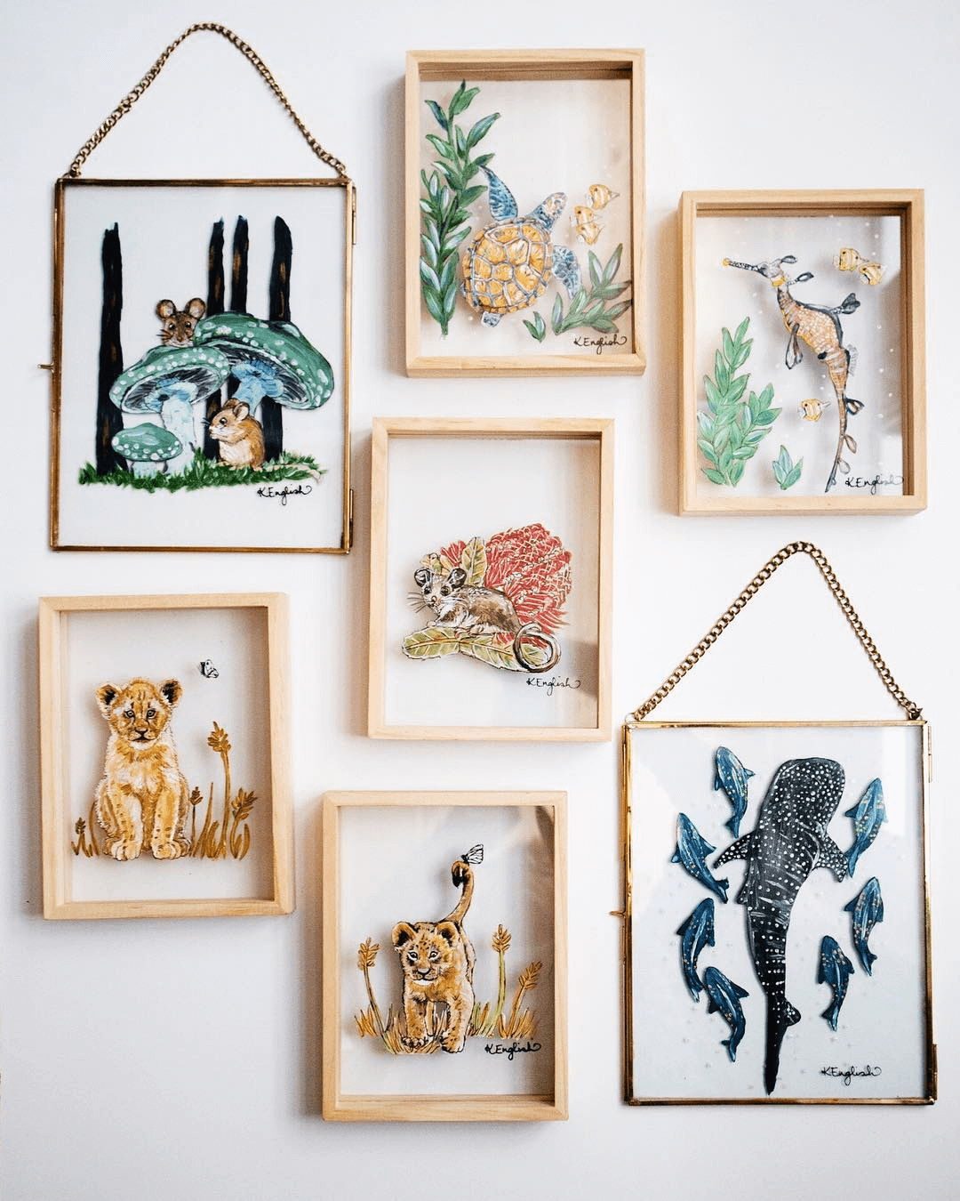 Glass animal portraits in a realistic painting style hanging on a white wall.