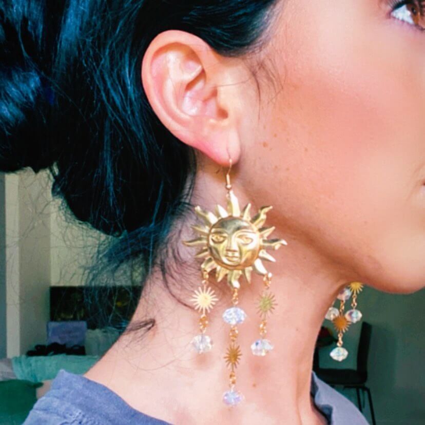 Side profile of Holly wearing gold handmade copper earrings with a celestial sun and stars.