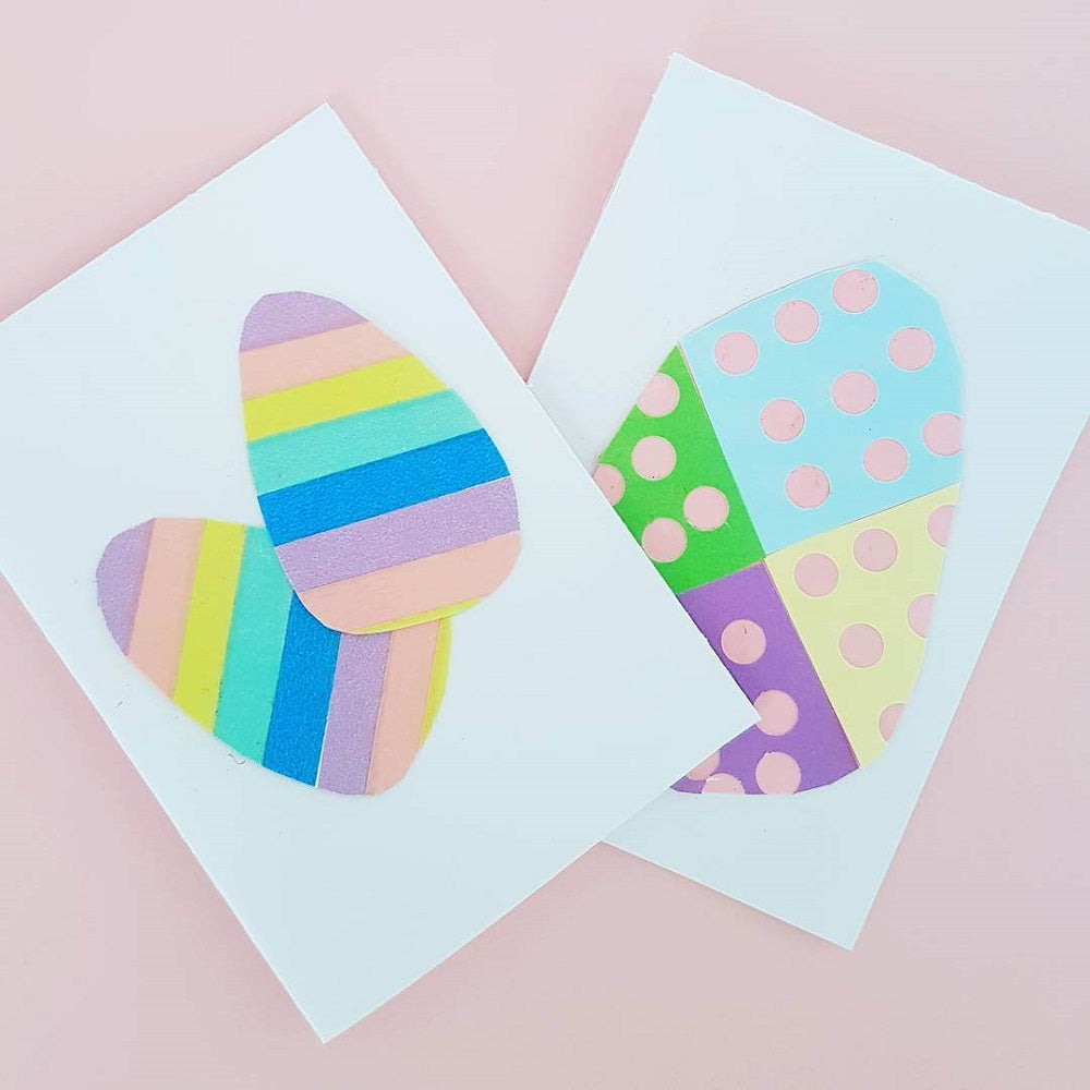 Two Easter egg cards made from cardboard, paper and coloured tape laying on a pastel pink background.