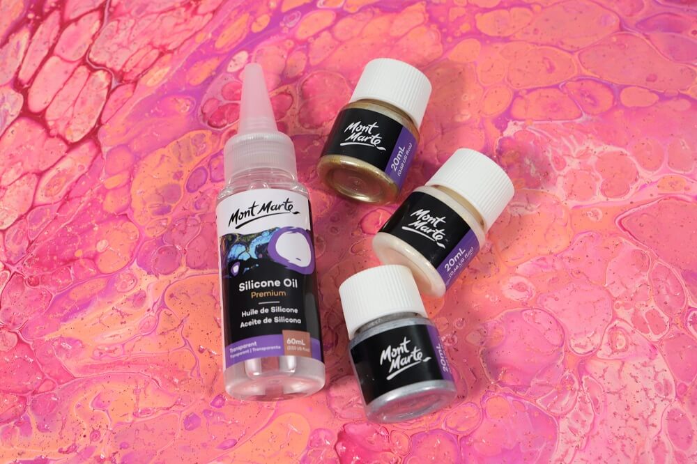 A silicone oil and three premium foil paint pots side by side on a pink marble canvas.