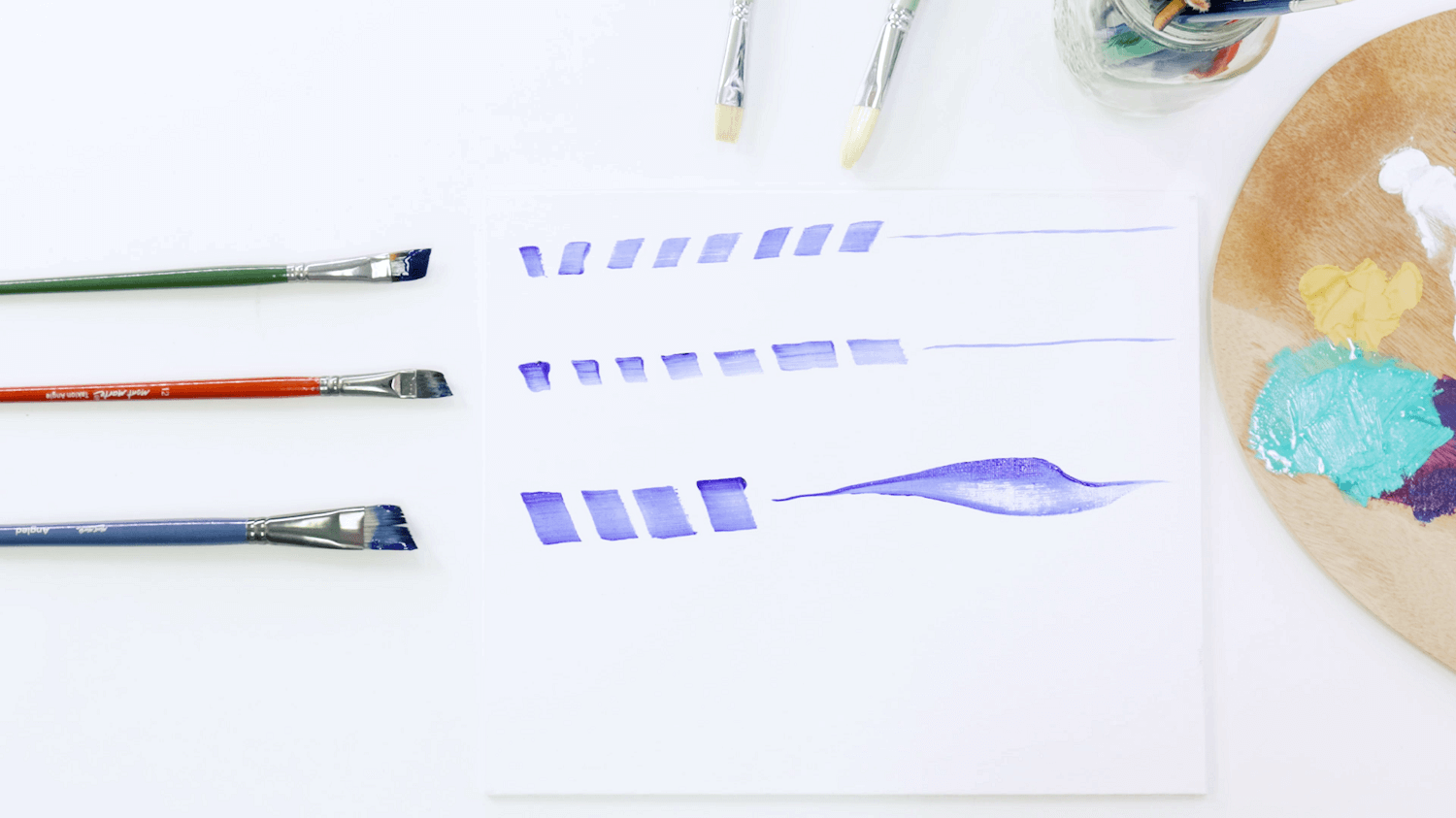 Angled brushes lined up next to pale blue lines of paint using the various sizes of oil paint brush.