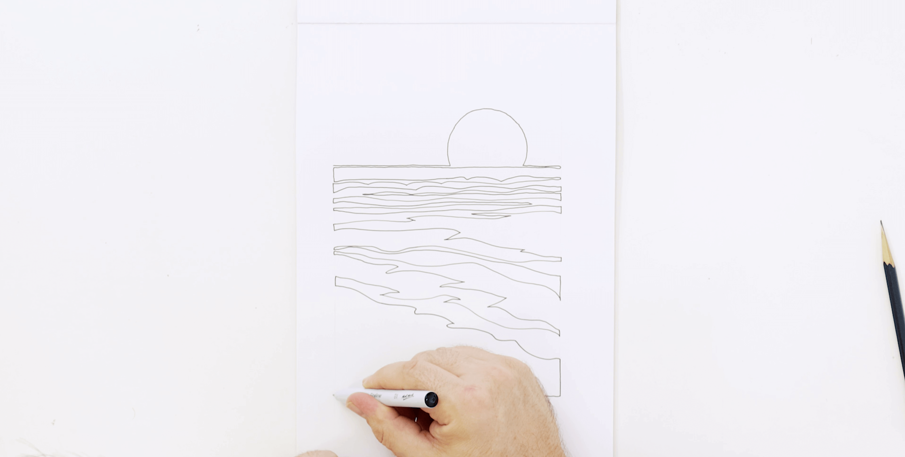 Hand holding a marker to create a continuous line landscape of a beach.