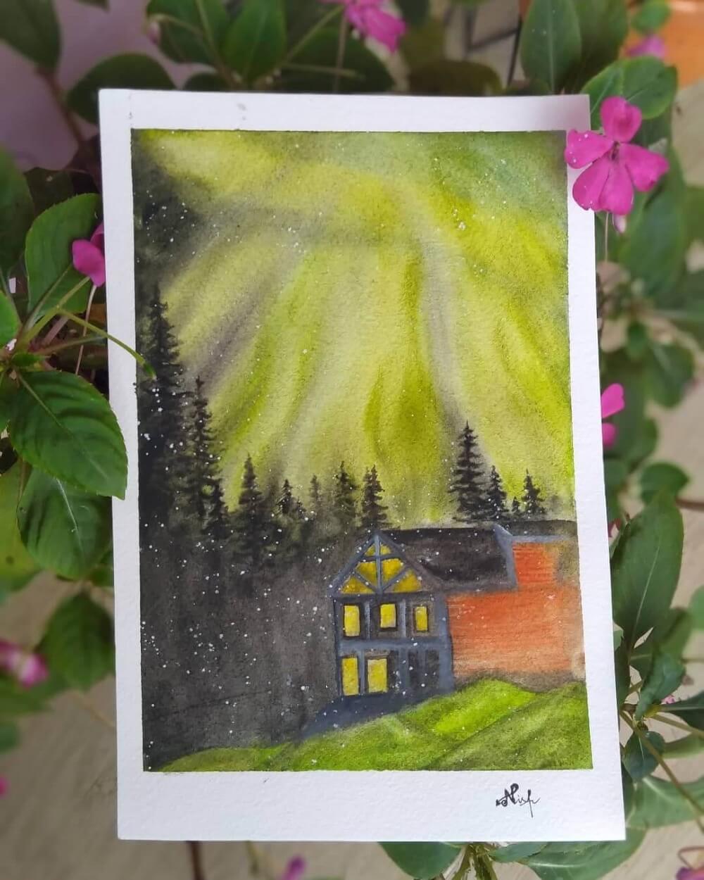 Painting of the Northern Lights on paper resting on purple flowers.