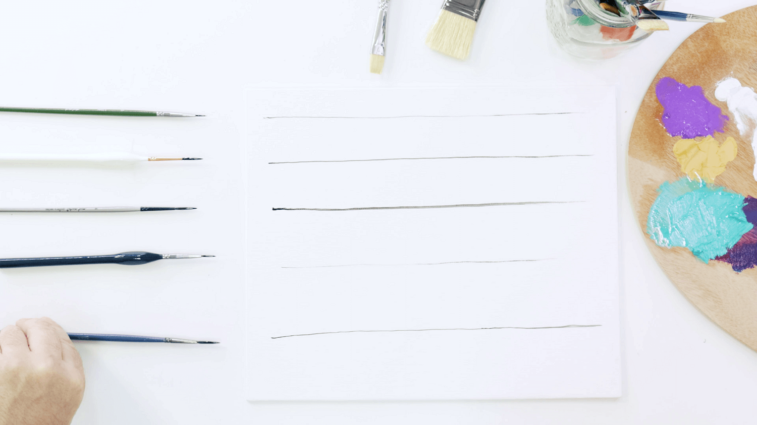 Four detailer brushes next to black oil paint lines made with each brush.