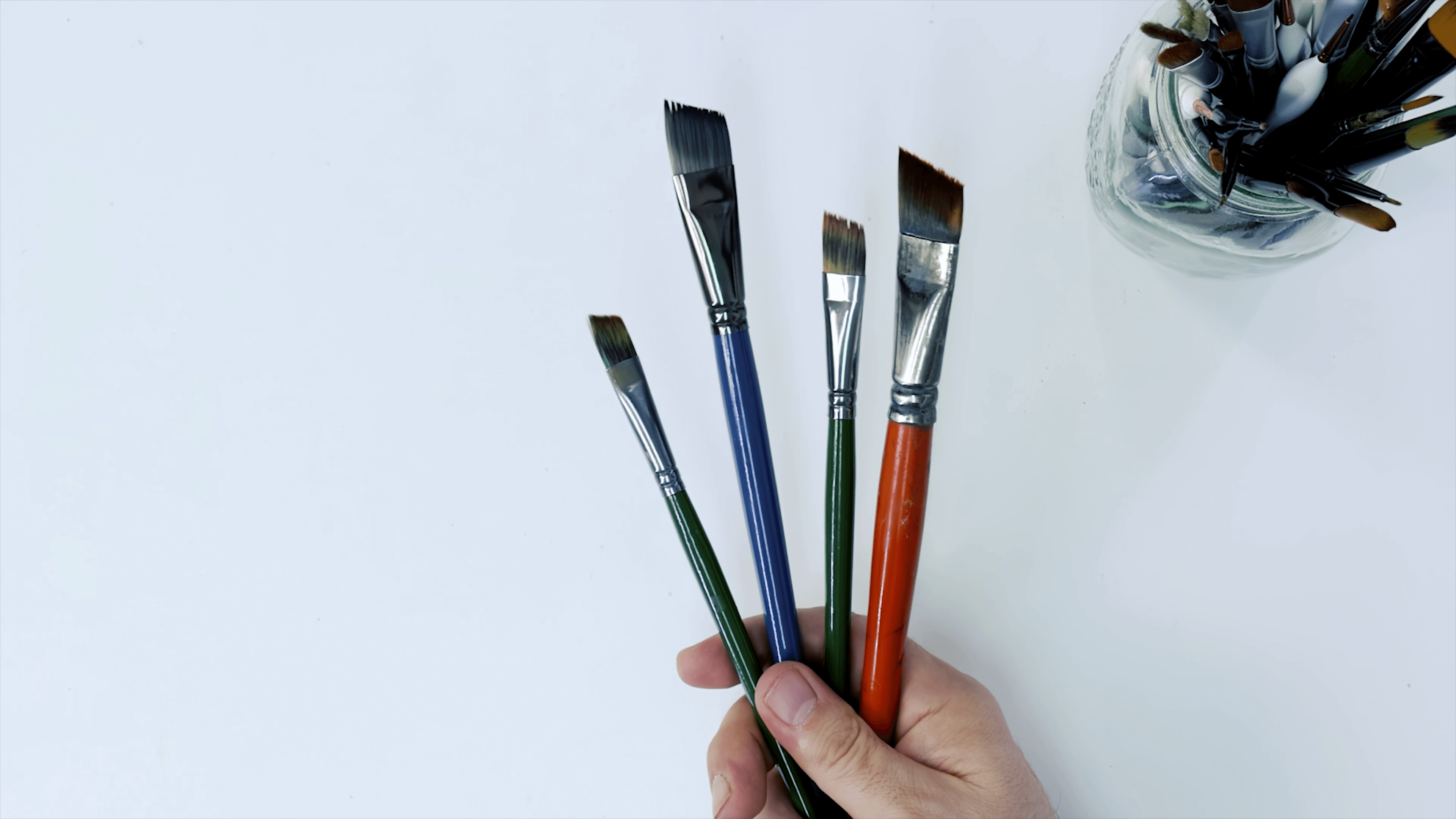 Four different sized angle brushes being held in hand.