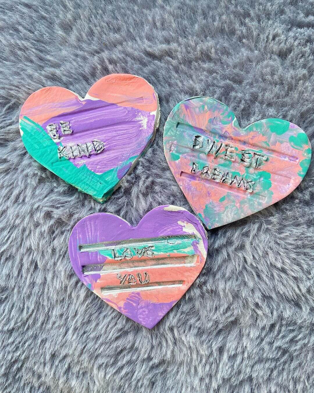 Three air dry clay heart coasters with various messages and ombre colours.