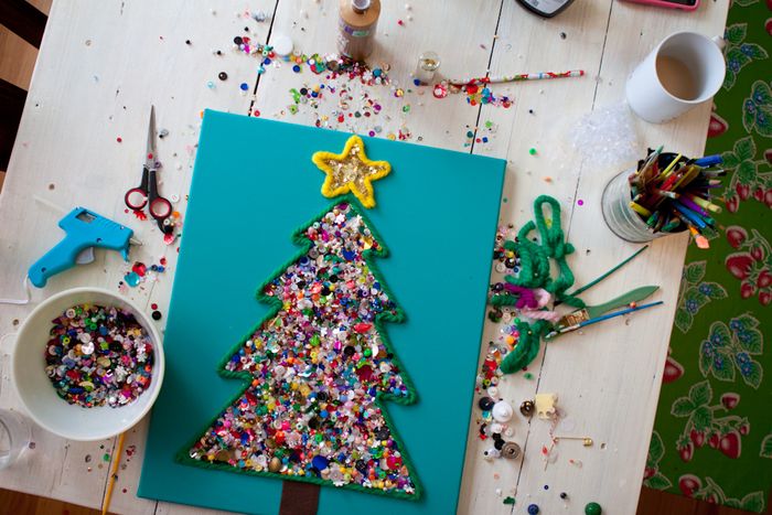 A glittery Christmas tree craft on bright blue paper.