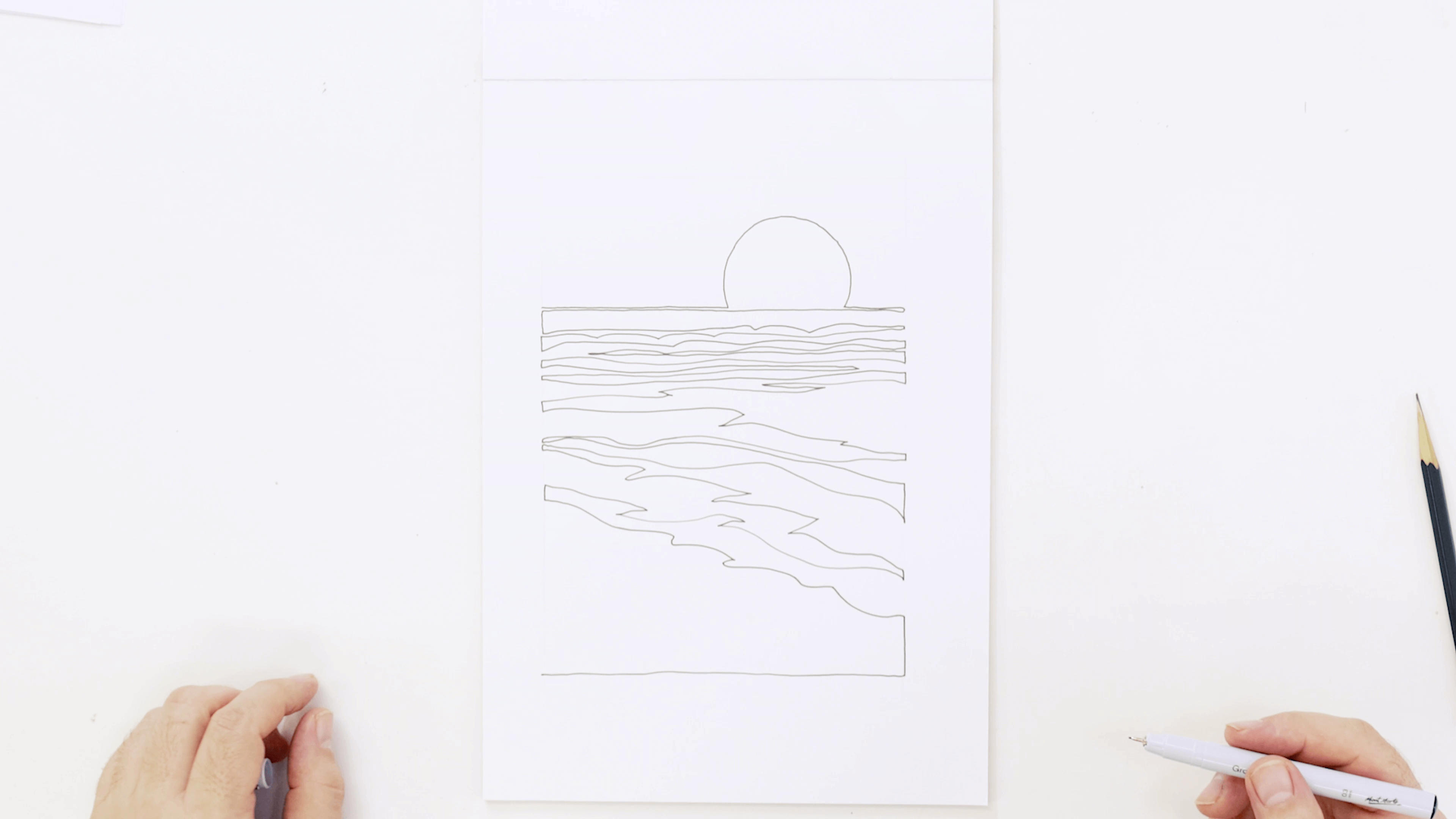 A beach landscape drawing drawn in a continuous line style with a hand holding the marker at the bottom right hand side of the page.