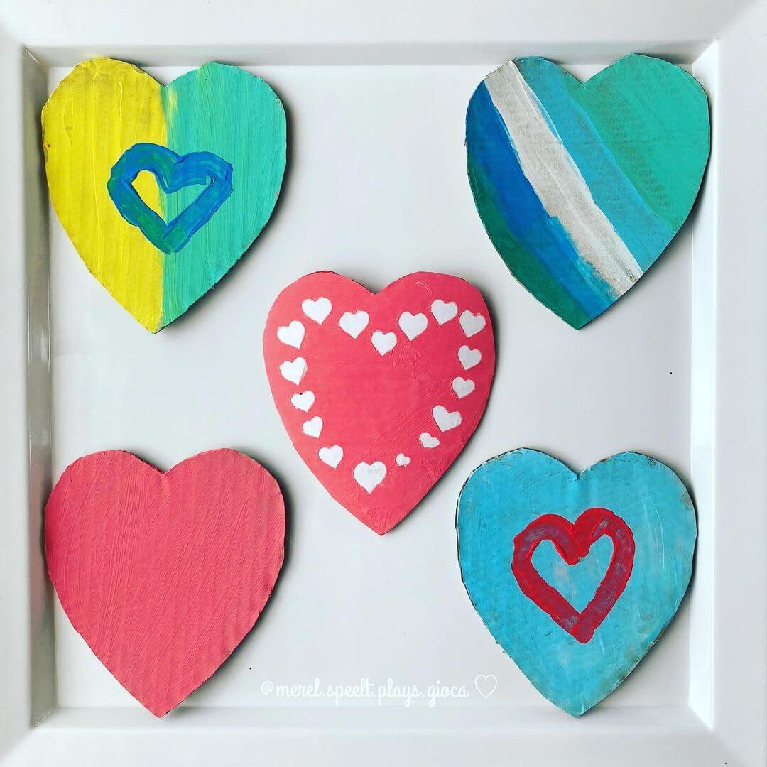 Five painted cardboard hearts with various colours and a sticker resist crafted heart in the middle.