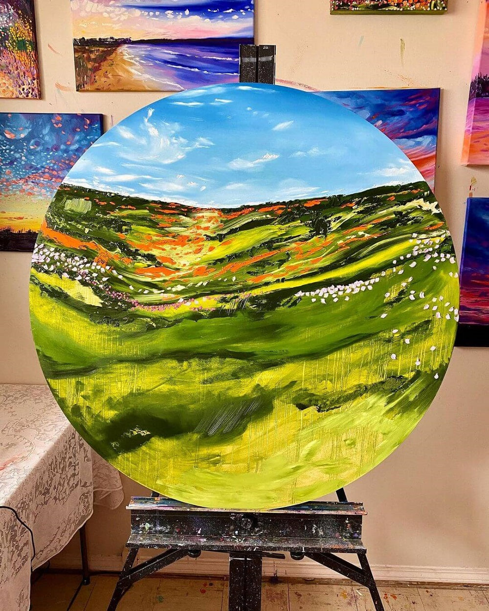 A large circular canvas with an abstract green landscape made with layers and a palette knife by Carly Gordon.