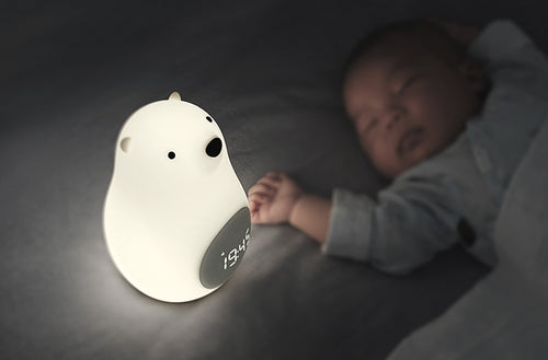 Child peacefully sleeping next to the illuminated Wake-Up Bear Alarm Clock showing the time.