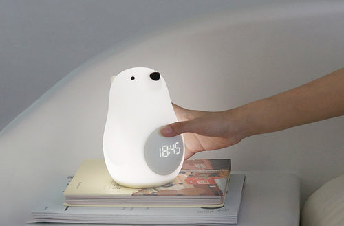 Hand adjusting the Wake-Up Bear Alarm Clock with stepless dimming function for customized brightness.