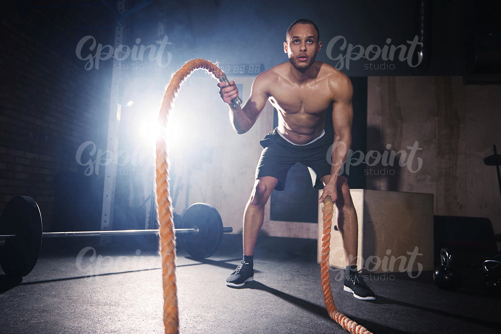 Motivated man throwing ropes at healthy club