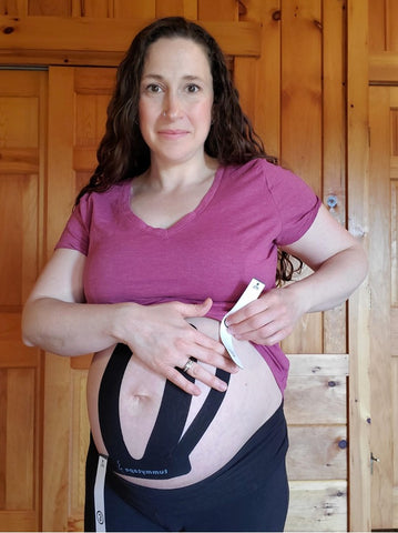 Physiotherapist applying tummytape to her baby belly.