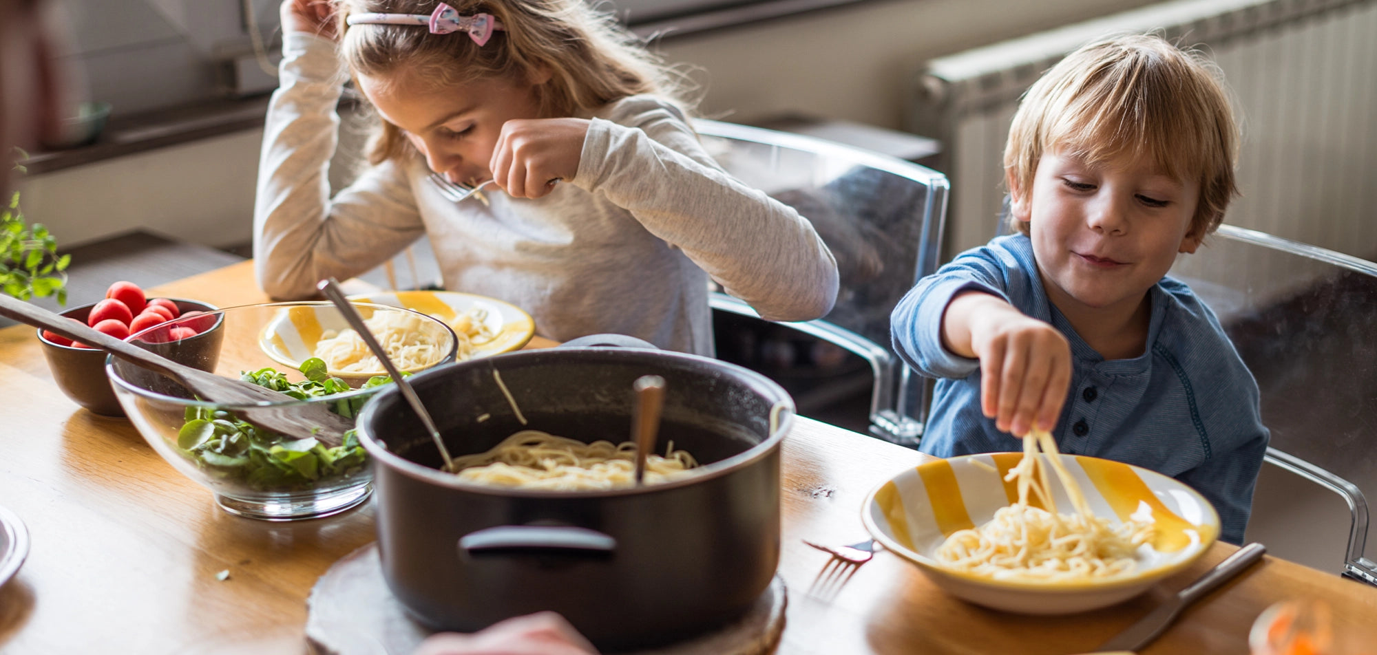 Children eating pasta at table