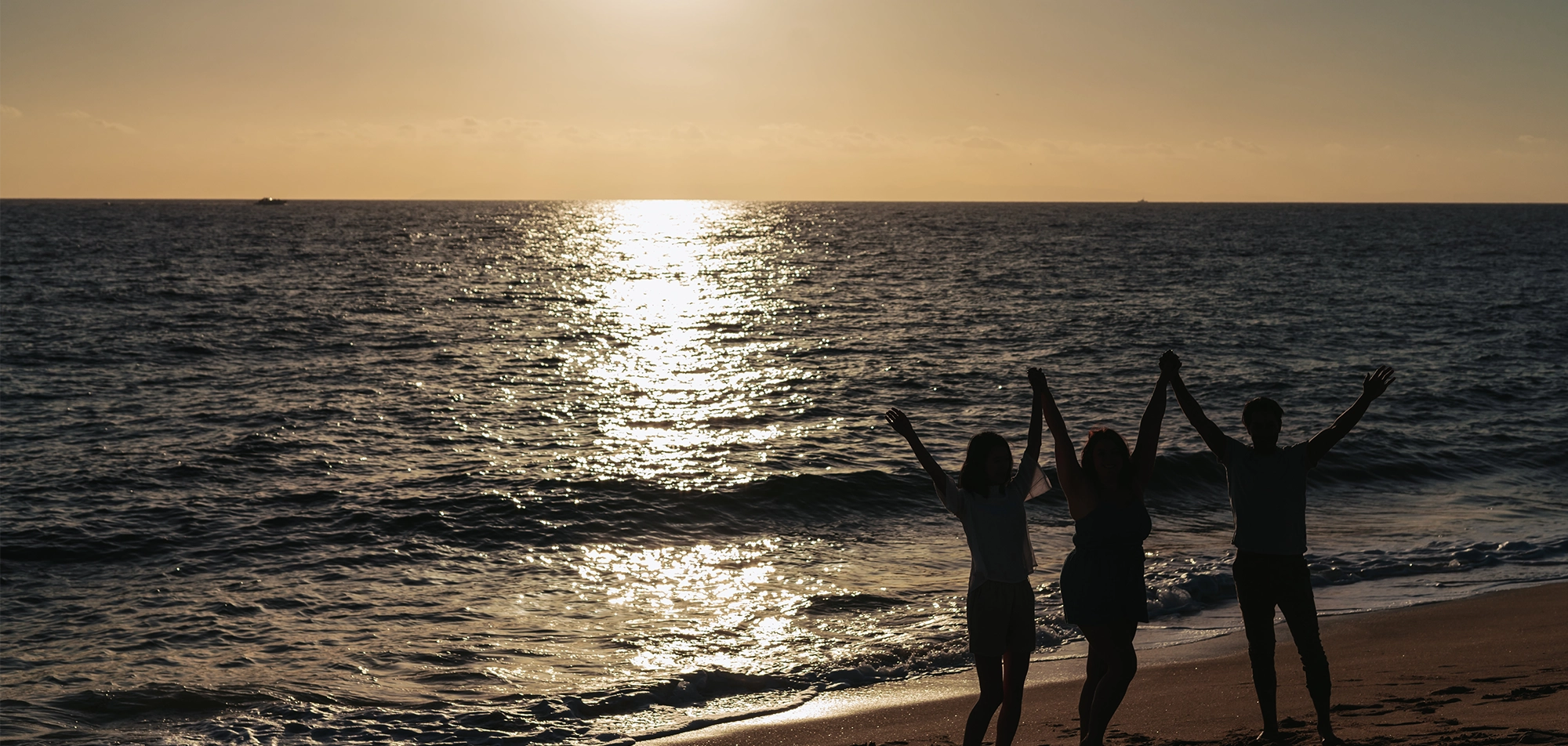 Friends on beach in front of ocean during sunset