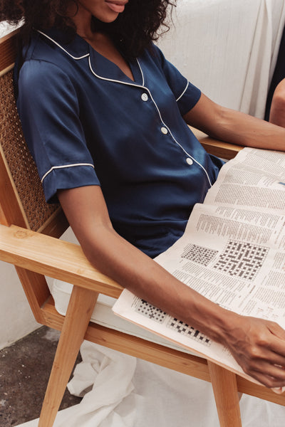 woman reading while wearing navy silk pyjama