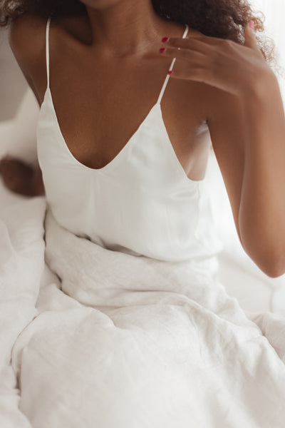 woman in bed wearing white silk camisole top