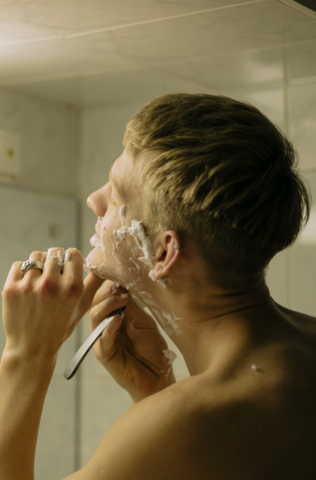 Man practicing grooming and skincare routine, shaving his face with precision, promoting clean and smooth skin.