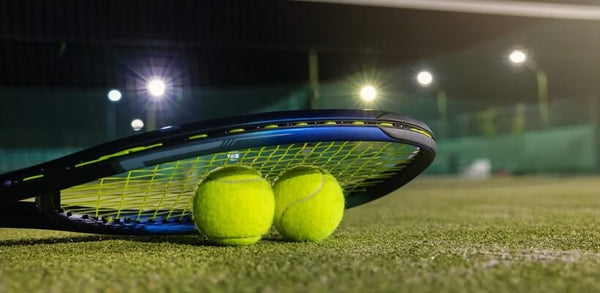 Image of an outdoor tennis court with two tennis balls and a racket.