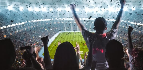 Image of a floodlit football stadium with fans.