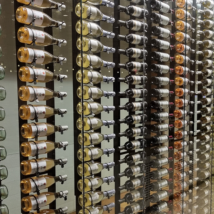 Multiple wine bottle resting on hanging wine racks inside a glass display case