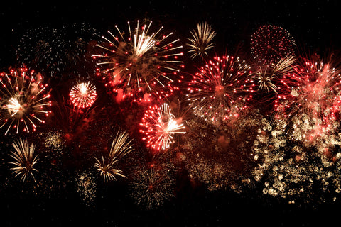 a cluster of fireworks, mostly red, against a black sky