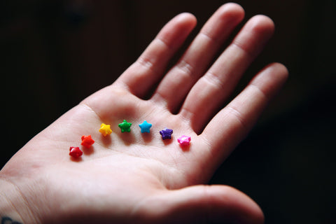 white hand holding hard candies in a various colors organized in a rainbow