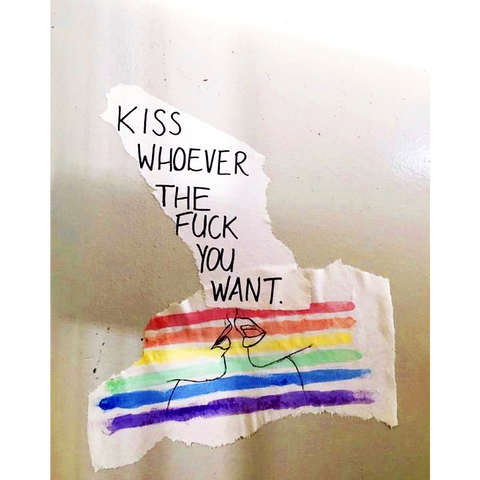 a ripped piece of paper that says "kiss whoever the fuck you want" with a rainbow painted over a line drawing of two female-presenting lips kissing