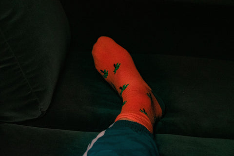 a foot in a red printed sock on a green velvet couch