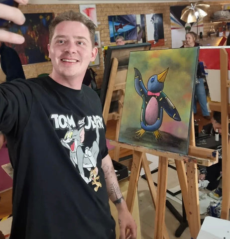 Artist standing in front of penguin painting 